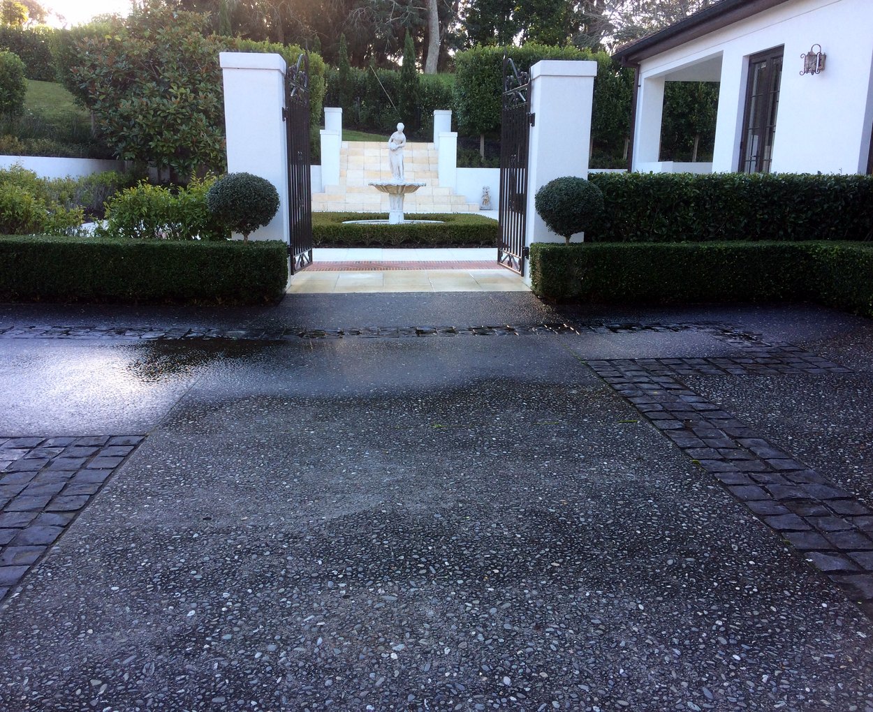 Pillared commercial entrance with clipped hedging and a water feature