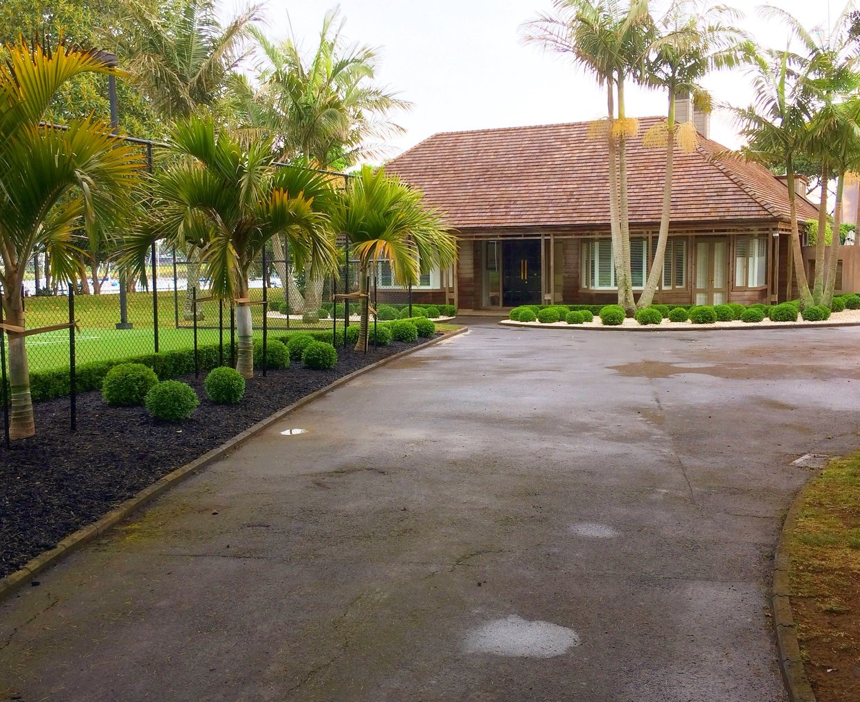 Sweeping commercial driveway lined with palms and topiary